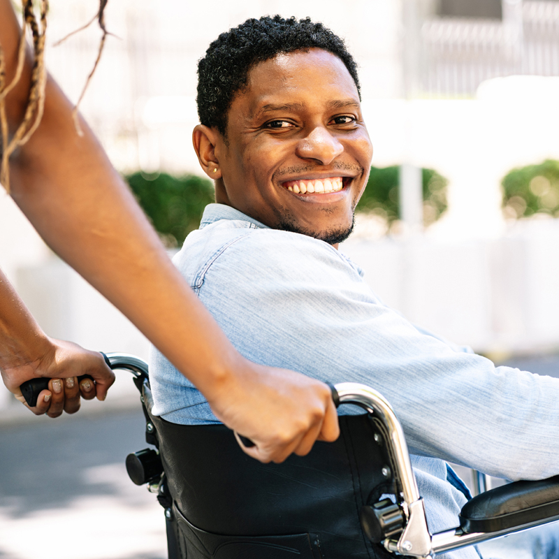 Man in a wheelchair smiling and looking at camera.